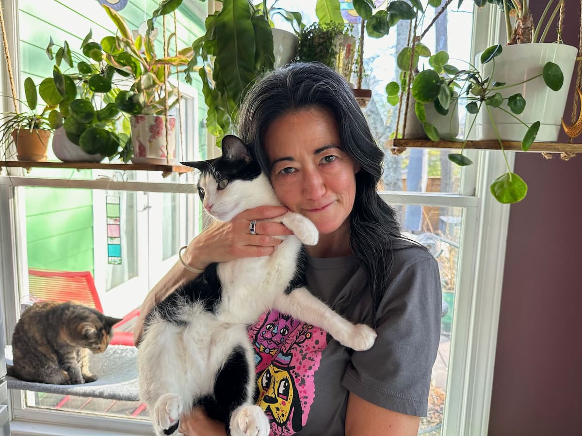 Woman cuddling a black and white cat.