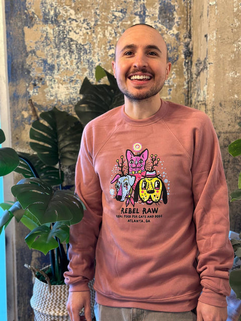 Man posing with arms at side in mauve Rebel Raw sweater.