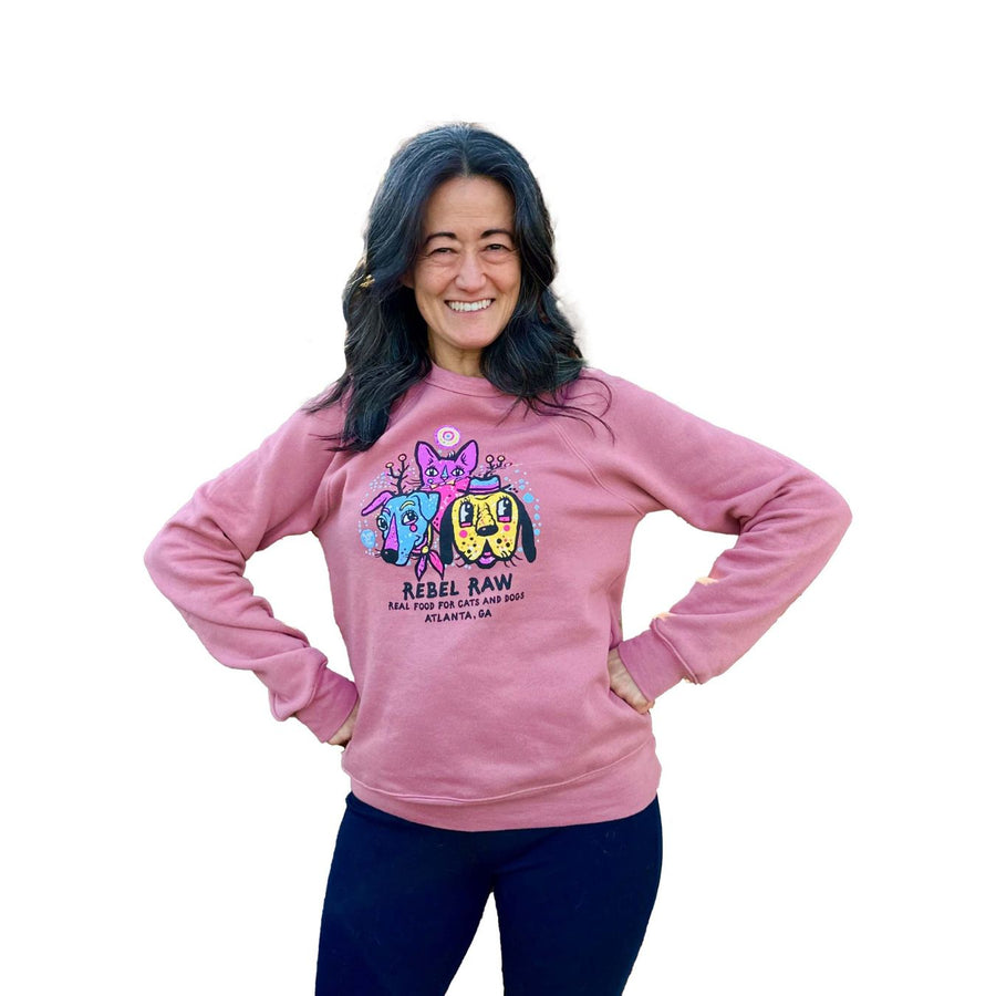 Woman posing with arms on hips in mauve Rebel Raw sweater.